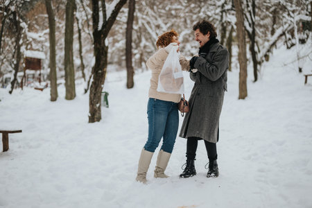Two friends laughing together on a snowy winter day outdoorsの写真素材
