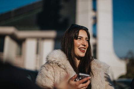 Smiling woman enjoying outdoors with a phone on a sunny dayの写真素材