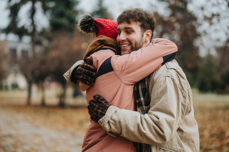 Joyful moment of two friends embracing outdoors on a cold autumn dayの写真素材