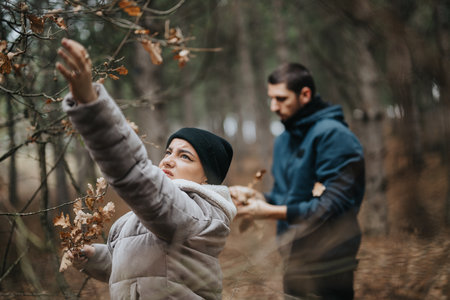 Couple Spending Time Outdoors Collecting Leaves in Winterの写真素材