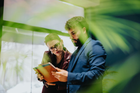 Two business people reviewing documents in a modern office workspaceの写真素材