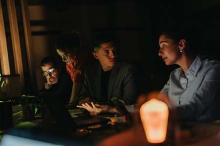 A group of business people working diligently on a project in a dimly lit office.の写真素材