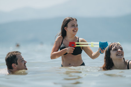 Friends enjoy water games with a squirt gun on a sunny dayの写真素材