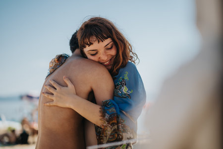 Close-up of friends embracing warmly on a sunny beachの写真素材