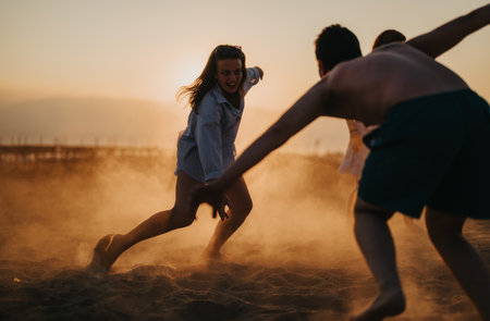 Friends enjoying a playful sunset activity on the sandy beachの写真素材