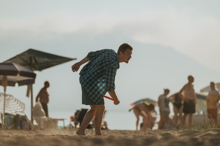 Man enjoying frisbee game on the beach during sunny summer afternoonの写真素材