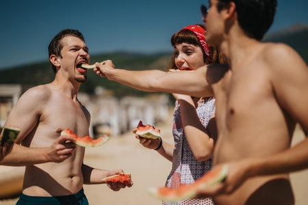Friends enjoying summer outdoors while sharing watermelon on a sunny dayの写真素材
