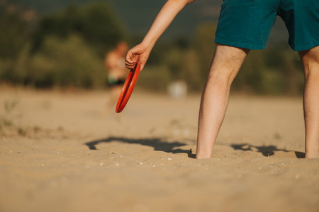 Man playing frisbee on a sandy beach during a sunny summer dayの写真素材
