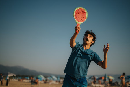 Young man playing paddle ball on a sunny crowded beach dayの写真素材
