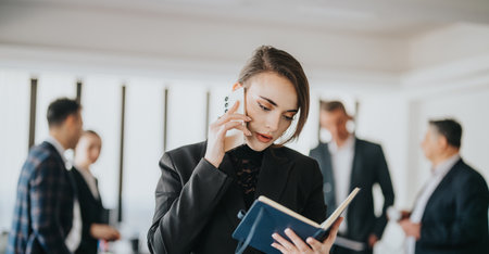 Professional businesswoman discussing work tasks on the phone in office environmentの写真素材