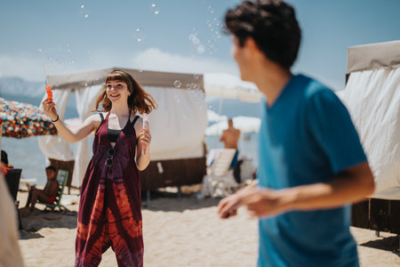 Joyful friends enjoying bubbles together on a sunny day at the beachの写真素材