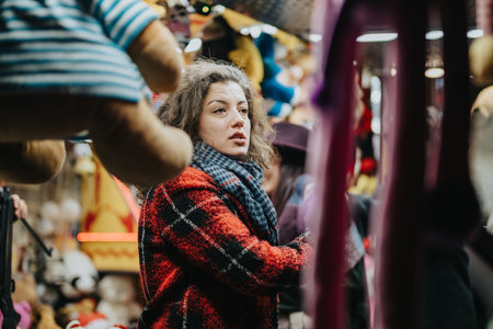 Woman shopping at a busy market surrounded by plush toys and winter decorationsの写真素材