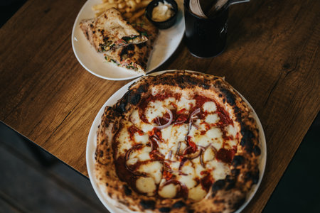 Freshly baked pizza and sandwich served on a wooden table
