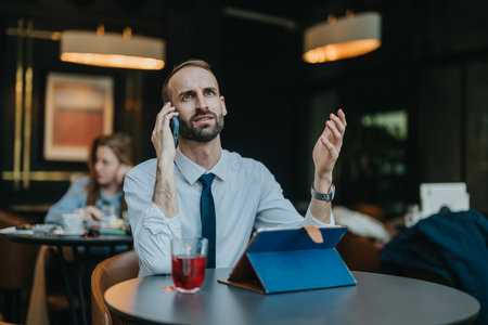 Business professional on a phone call gesturing in a cafe settingの写真素材