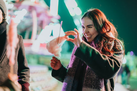 Smiling friends enjoying cotton candy at a festive winter eventの写真素材