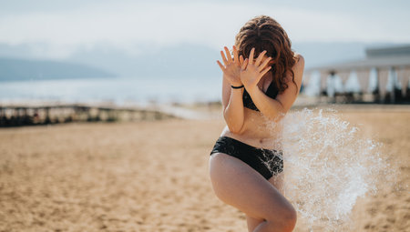 Young woman enjoying a playful moment at a sunny beachの写真素材