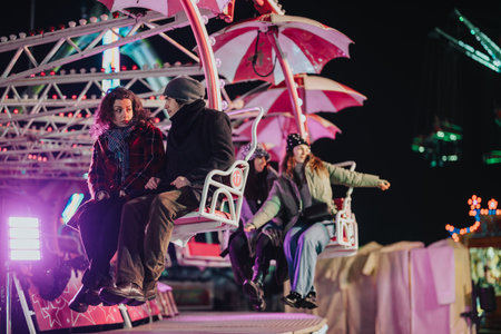 Group of friends enjoying a night amusement park ride under colorful lights