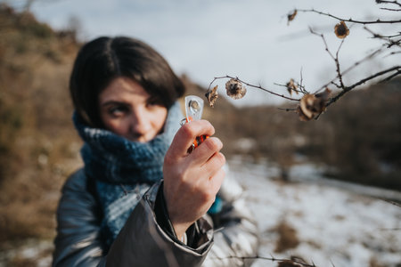 Woman examining winter nature up close with keen curiosity