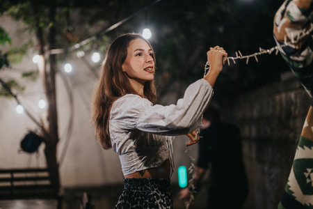 Woman decorating outdoors under a string light for a festive evening gathering