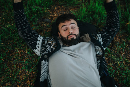 Man relaxing in a park wearing a cozy sweater on a fall dayの写真素材