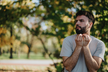 Thoughtful man enjoying a peaceful moment in a serene green parkの写真素材