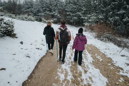 Friends walking in a snowy forest trail during winterの写真素材