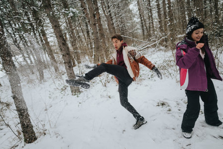 Friends enjoy playful moments in snowy winter forest sceneryの写真素材