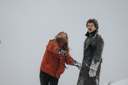Two friends enjoying playful moments in the snow during a winter dayの写真素材