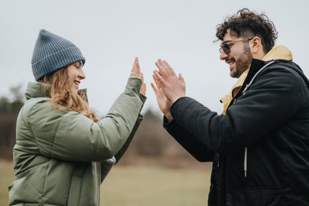 Two friends enjoy outdoor fun by high-fiving on a cloudy dayの写真素材