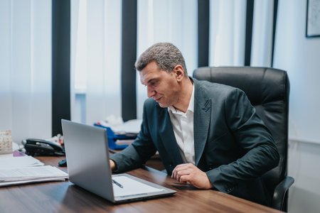 Professional businessman focused on work at desk in modern office settingの写真素材