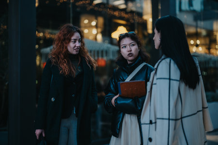 Three women discussing together outdoors in a modern urban settingの写真素材