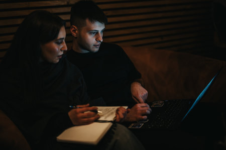 Two people collaborating on a project using a laptop and notebookの写真素材