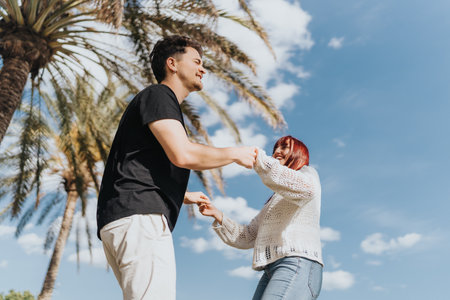 Young couple dancing and enjoying their time outdoors under clear skies in a tropical settingの写真素材