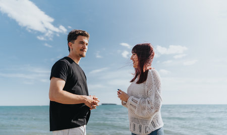 A young couple enjoying a sunny day together by the sea, capturing moments of joy and tranquility under the clear blue sky.の写真素材
