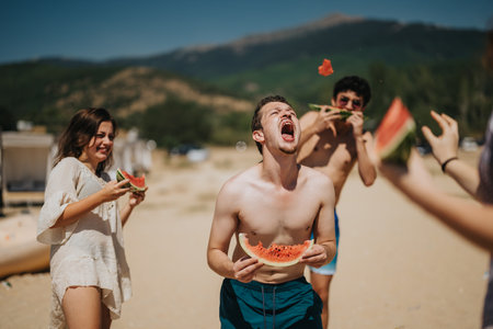 Group of friends having fun and enjoying watermelon at the beachの写真素材