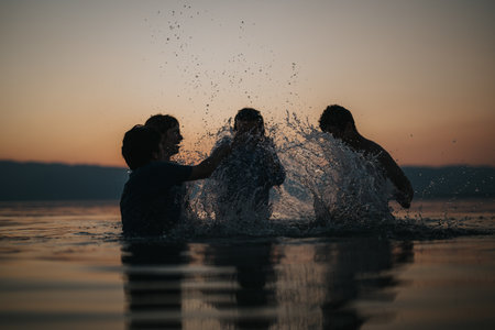 Friends enjoying playful water splashes during a sunset