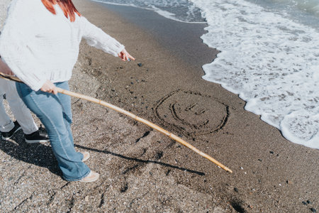People Drawing a Smiley Face in the Sand on a Seaside Vacationの写真素材