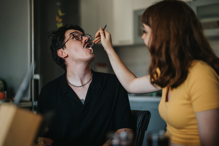 Woman feeding man with fork during casual indoor mealの写真素材