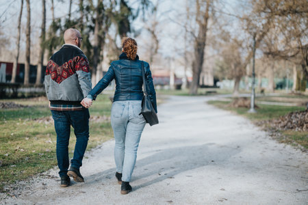 Couple walking hand in hand along a scenic park path