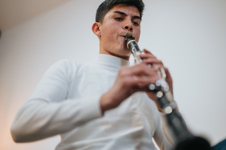 Young man playing a clarinet with focus on musical performanceの写真素材