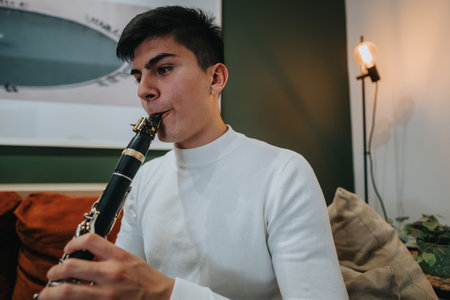 Young man playing a clarinet at home in a cozy modern setting
