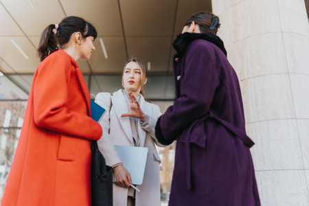 Three businesswomen collaborating and discussing strategies in an outdoor settingの写真素材