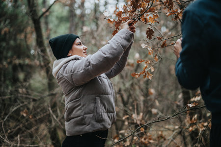 Woman picking leaves on an autumn forest outing wearing warm winter clothing