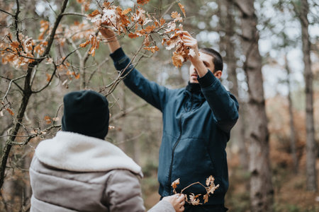 Two individuals engaging with autumn nature in a forest setting