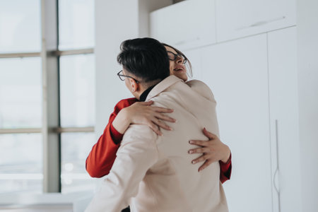 Coworkers sharing warm hug in modern office kitchenの写真素材