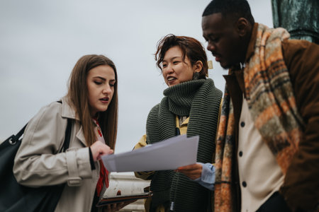 Group of friends reviewing documents together outdoors in casual attire