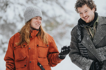 Two friends enjoy a snowy outdoor moment, smiling and dressed warmly in winter clothingの写真素材