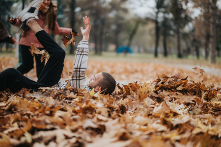 Playful moments captured in an autumn park setting with individuals enjoying leavesの写真素材