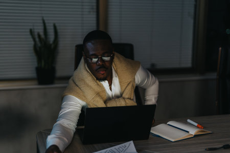 Businessman working late at night in dimly lit officeの写真素材
