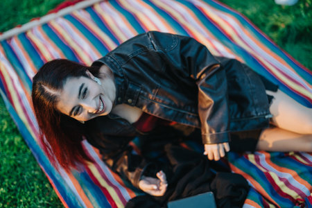 Smiling woman relaxing on a colorful blanket outdoors in the grassの写真素材